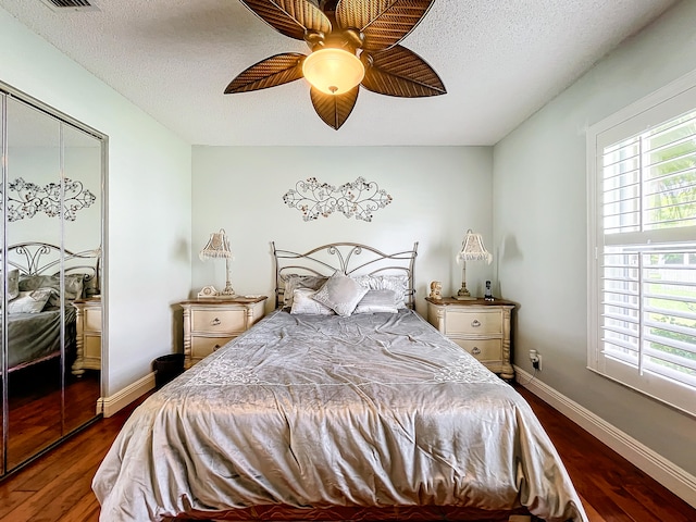 bedroom with ceiling fan, dark wood-type flooring, a closet, and a textured ceiling