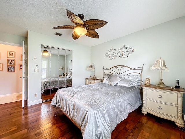 bedroom with ceiling fan, a closet, a textured ceiling, and dark wood-type flooring