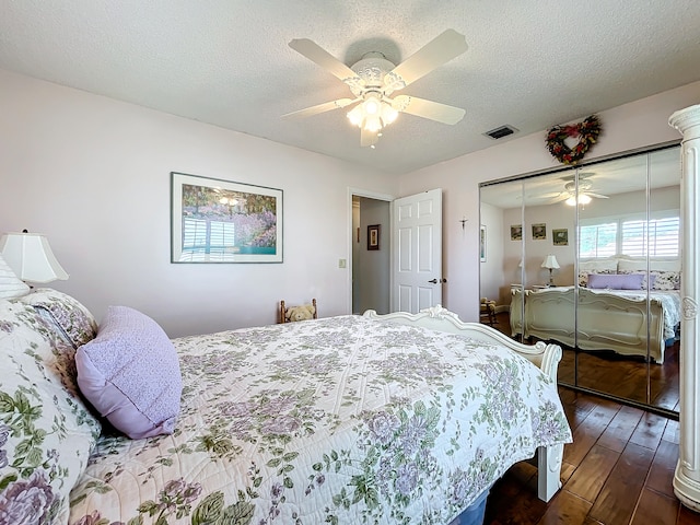 bedroom with ceiling fan, dark wood-type flooring, a closet, and a textured ceiling