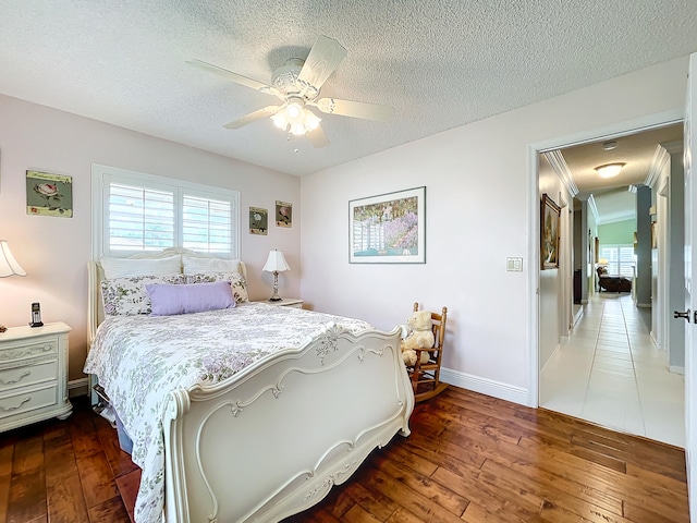 bedroom featuring ceiling fan, wood-type flooring, ornamental molding, and a textured ceiling