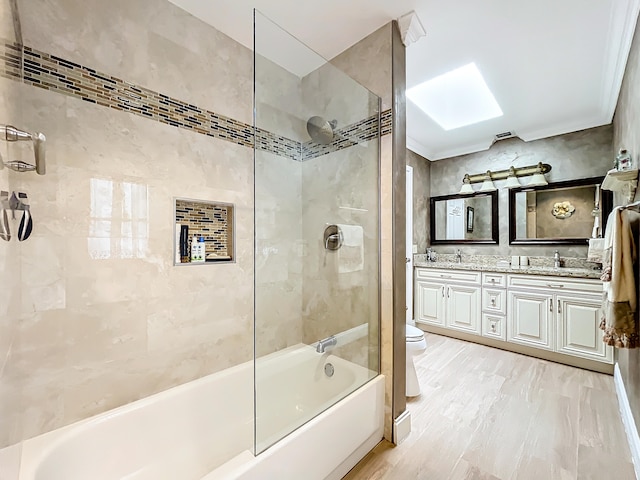 full bathroom featuring ornamental molding, a skylight, tiled shower / bath combo, vanity, and toilet