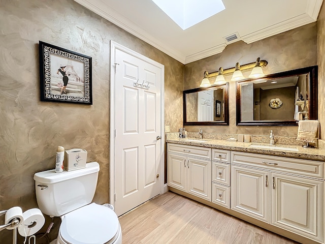 bathroom featuring toilet, a skylight, vanity, wood-type flooring, and crown molding