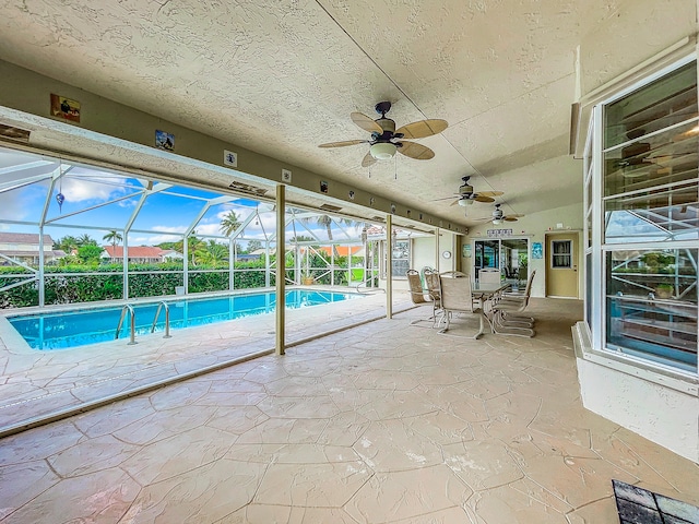 view of swimming pool featuring ceiling fan, glass enclosure, and a patio