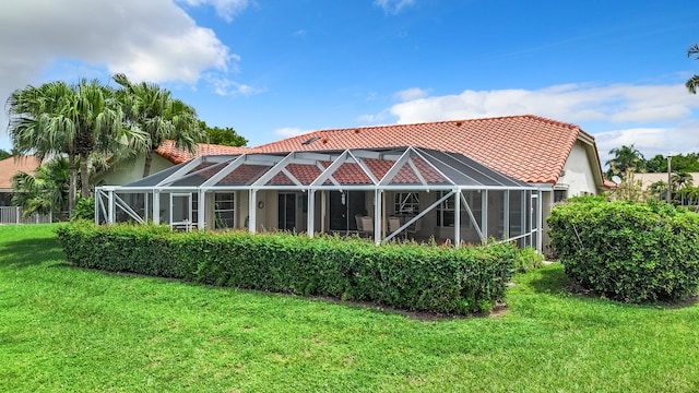 rear view of house with glass enclosure and a lawn