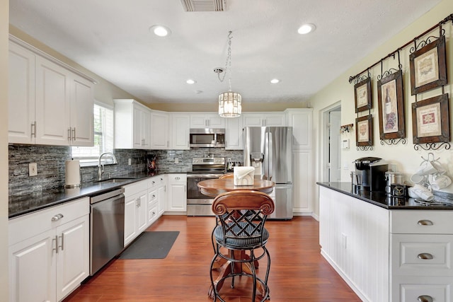 kitchen featuring dark hardwood / wood-style flooring, white cabinetry, sink, and appliances with stainless steel finishes