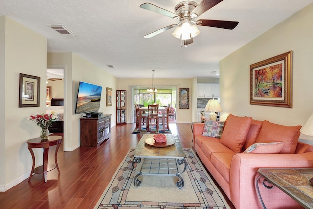 living room with a textured ceiling, ceiling fan with notable chandelier, and dark hardwood / wood-style floors