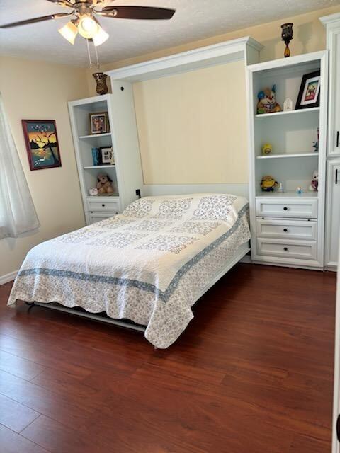 bedroom with dark hardwood / wood-style floors and ceiling fan