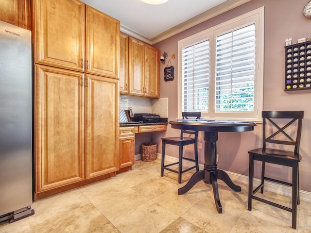 kitchen featuring tasteful backsplash, stainless steel fridge, built in desk, and ornamental molding