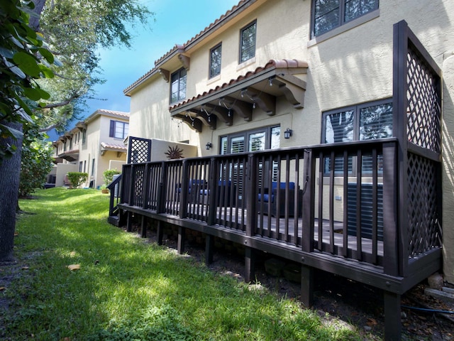 rear view of property featuring a wooden deck and a lawn