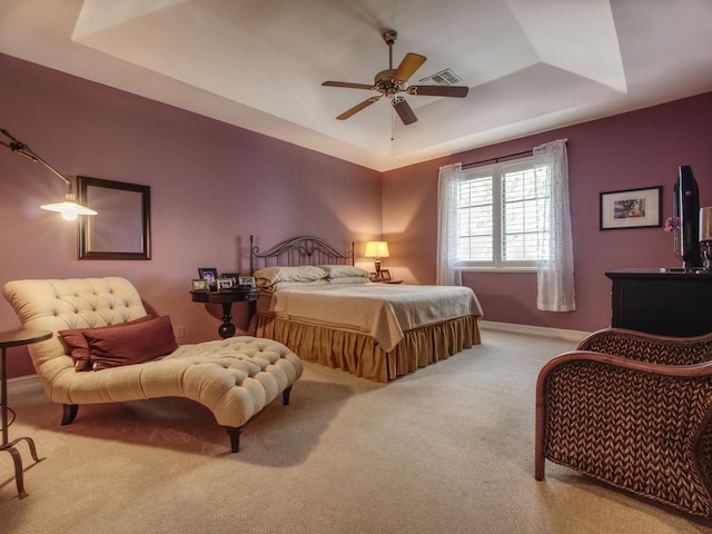 bedroom featuring a tray ceiling, ceiling fan, and light carpet