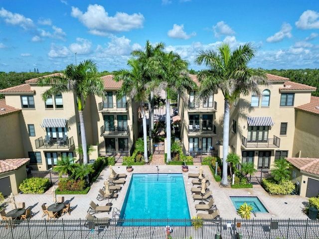 pool featuring fence, a hot tub, and a patio