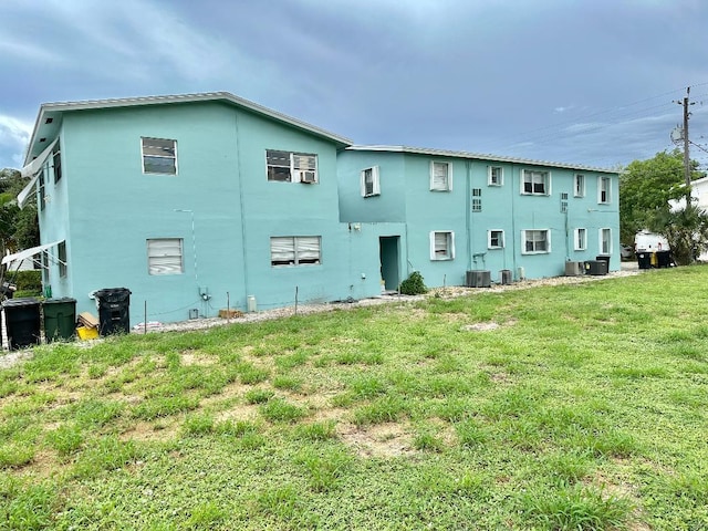 back of house featuring a yard and central air condition unit