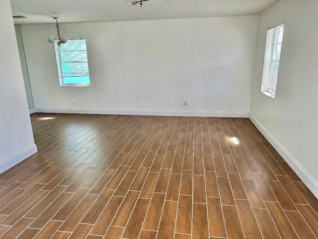 spare room with dark hardwood / wood-style floors and a notable chandelier