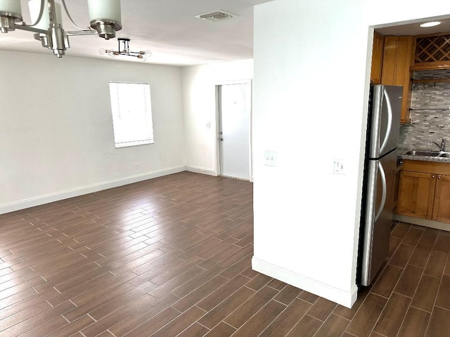 kitchen featuring sink, dark hardwood / wood-style floors, stainless steel refrigerator, and decorative backsplash