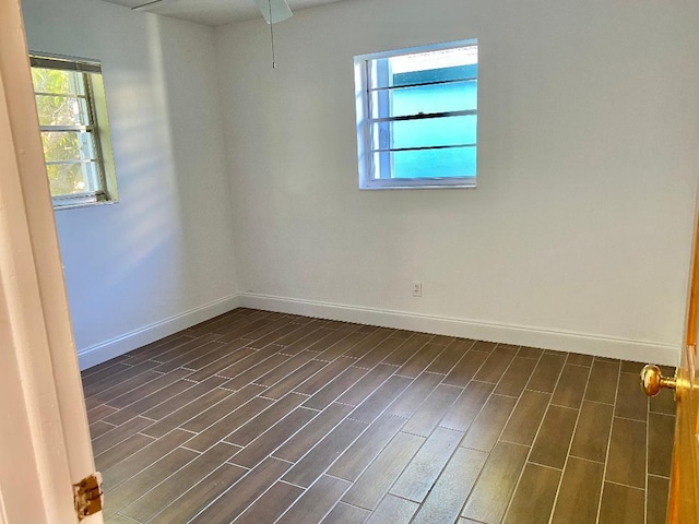 spare room featuring a healthy amount of sunlight and dark hardwood / wood-style flooring