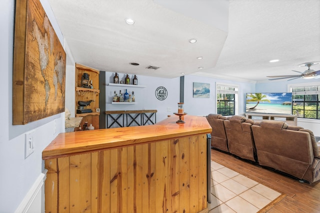 kitchen featuring ornamental molding, a textured ceiling, light hardwood / wood-style flooring, and ceiling fan