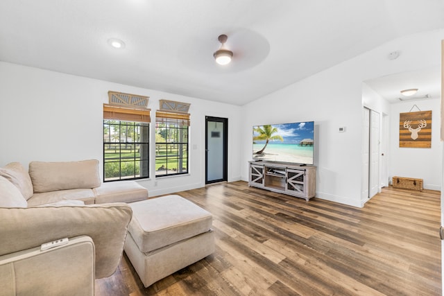 living room featuring ceiling fan, dark hardwood / wood-style floors, and vaulted ceiling