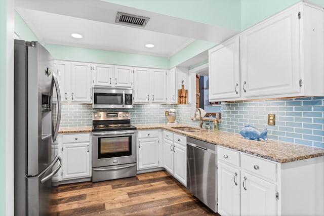 kitchen featuring dark wood-type flooring, backsplash, appliances with stainless steel finishes, and white cabinets