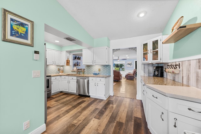 kitchen featuring dark hardwood / wood-style flooring, appliances with stainless steel finishes, tasteful backsplash, white cabinetry, and lofted ceiling