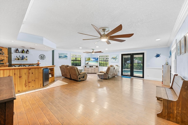 living room with crown molding, french doors, light wood-type flooring, ceiling fan, and a textured ceiling