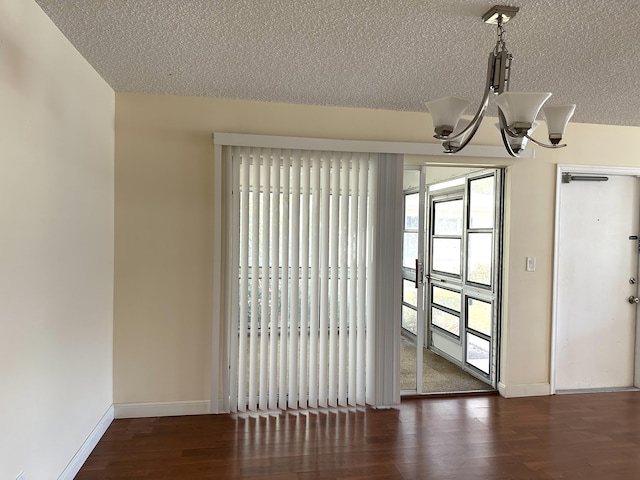 unfurnished dining area featuring a chandelier, a textured ceiling, and dark hardwood / wood-style flooring