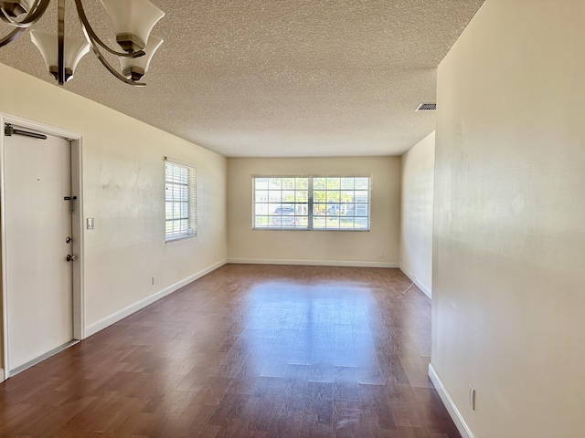 empty room with wood-type flooring and a textured ceiling