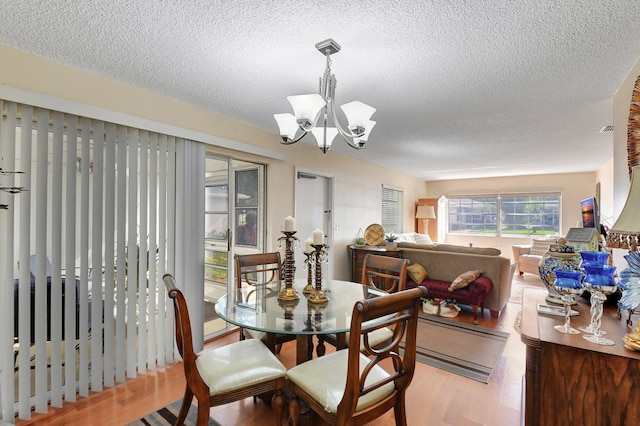 dining room with a chandelier, a textured ceiling, and light wood-type flooring