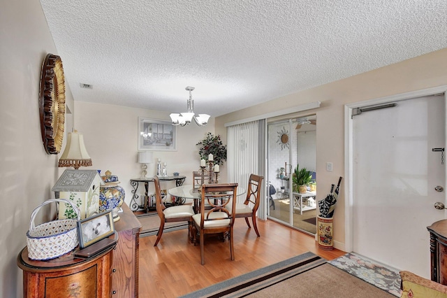 dining room featuring a notable chandelier, a textured ceiling, and light wood-type flooring