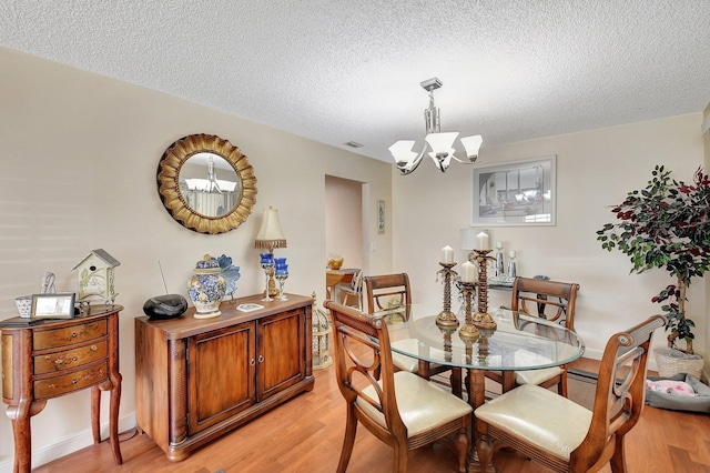 dining room featuring an inviting chandelier, light hardwood / wood-style flooring, and a textured ceiling