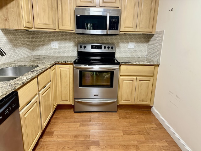 kitchen featuring sink, light brown cabinets, stainless steel appliances, light stone countertops, and light hardwood / wood-style floors