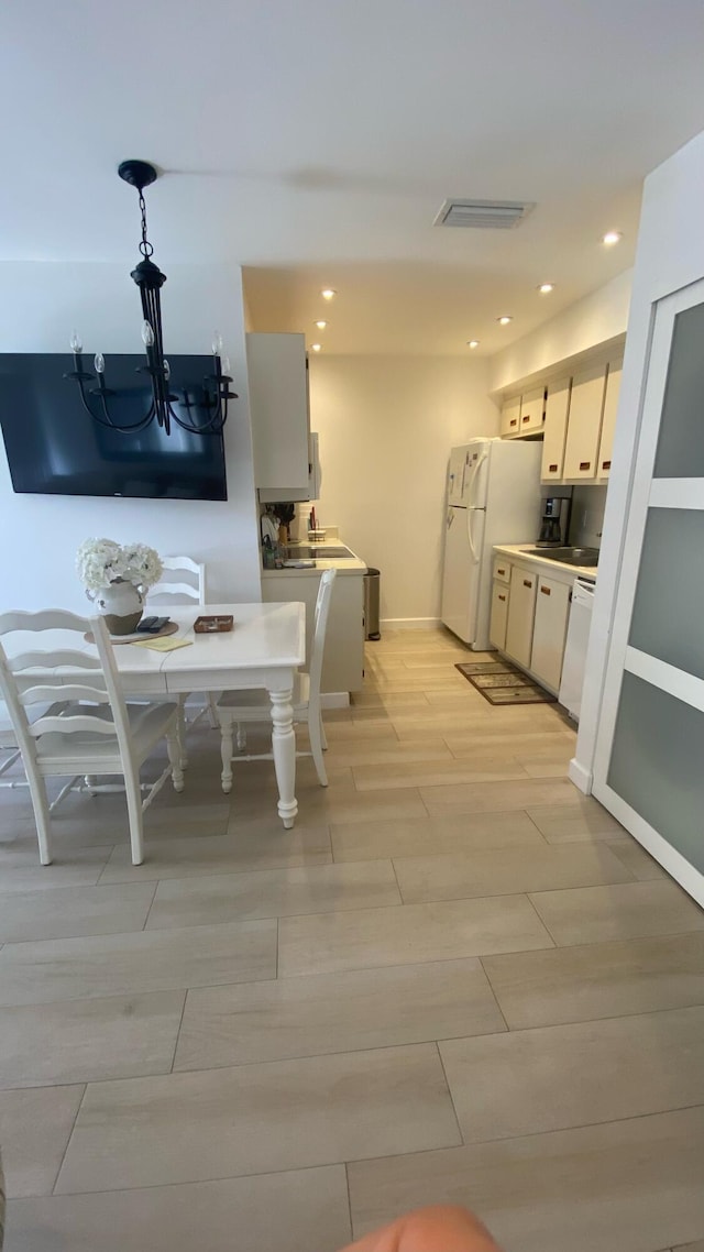 kitchen with pendant lighting, light wood-type flooring, and white appliances