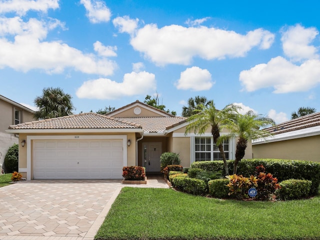 ranch-style house featuring decorative driveway, stucco siding, an attached garage, a tiled roof, and a front lawn