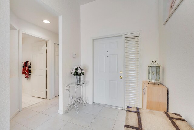 hall featuring light tile patterned flooring and vaulted ceiling