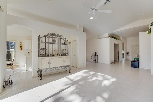 tiled empty room featuring ceiling fan with notable chandelier and vaulted ceiling