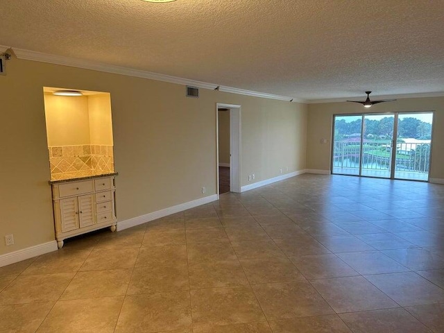 tiled empty room featuring ceiling fan, ornamental molding, and a textured ceiling