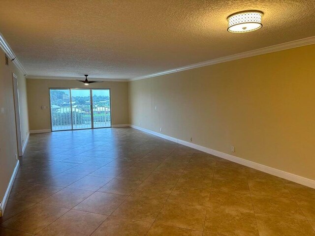 empty room with ornamental molding, a textured ceiling, and tile patterned flooring