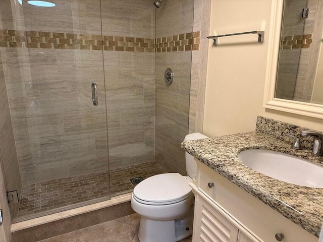 bathroom featuring tile patterned flooring, toilet, an enclosed shower, and vanity