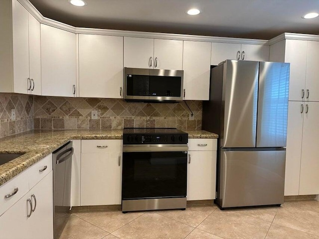 kitchen with white cabinets, decorative backsplash, appliances with stainless steel finishes, and light tile patterned flooring