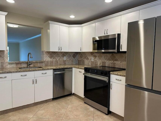 kitchen with dark stone counters, appliances with stainless steel finishes, sink, and backsplash