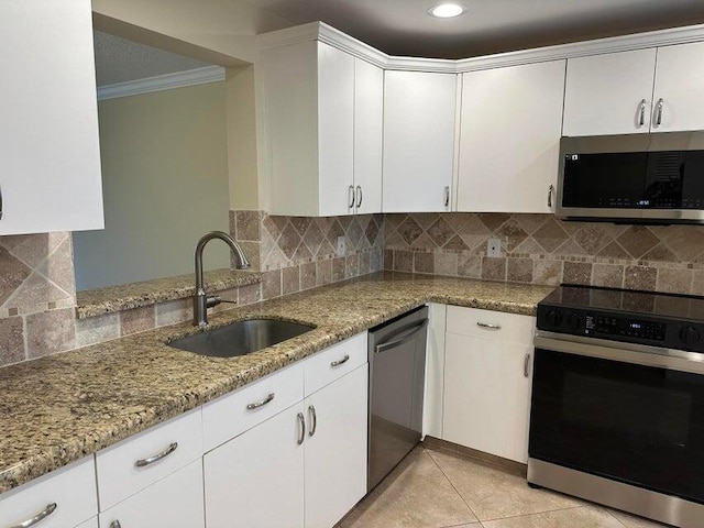 kitchen with backsplash, appliances with stainless steel finishes, ornamental molding, sink, and light stone countertops