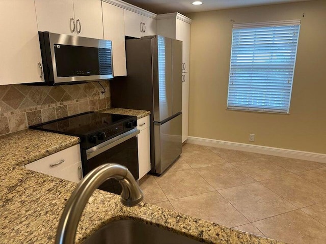 kitchen with appliances with stainless steel finishes, light stone countertops, decorative backsplash, and white cabinetry