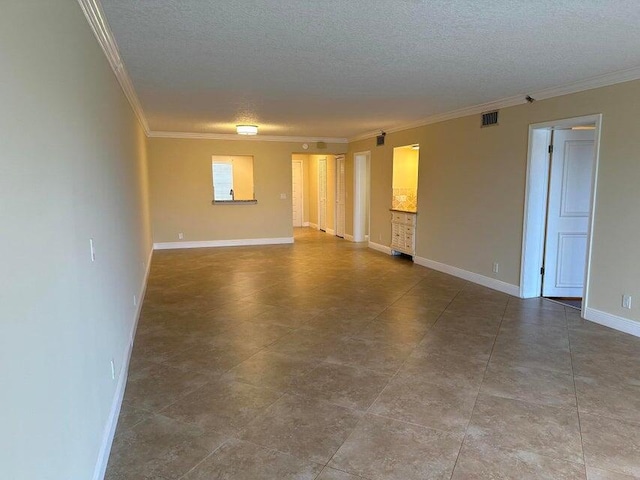 tiled empty room featuring ornamental molding and a textured ceiling