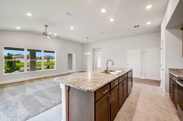 kitchen with lofted ceiling, a kitchen island with sink, sink, light stone countertops, and light tile patterned flooring