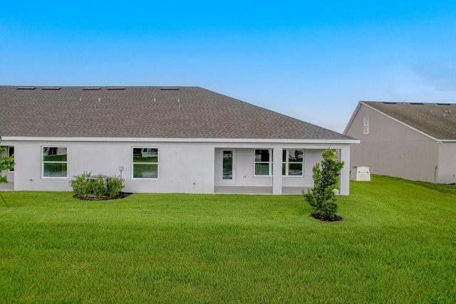 rear view of property featuring a lawn