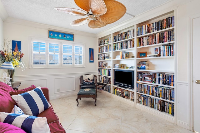 living area with ceiling fan, ornamental molding, a textured ceiling, and light tile patterned floors