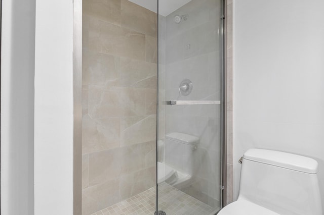 bathroom featuring toilet and a shower with shower door