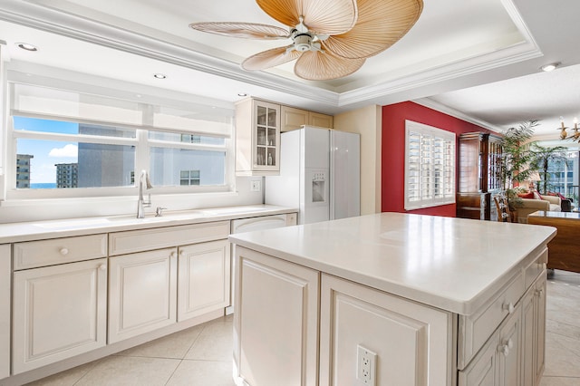 kitchen featuring ornamental molding, a tray ceiling, ceiling fan, white refrigerator with ice dispenser, and light tile patterned flooring