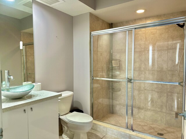 bathroom with toilet, a shower with door, and vanity