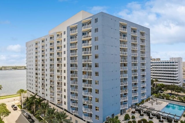 view of building exterior with a community pool and a water view