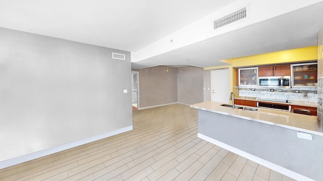 kitchen featuring wall oven, light hardwood / wood-style flooring, kitchen peninsula, and sink